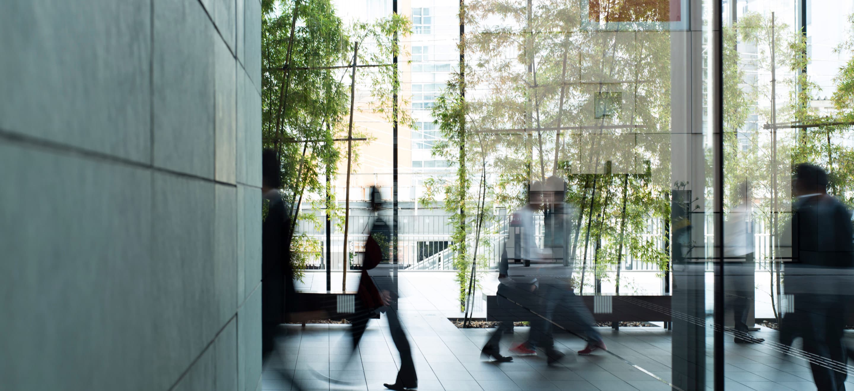 Équipes se croisant dans un hall d'entreprise vitré